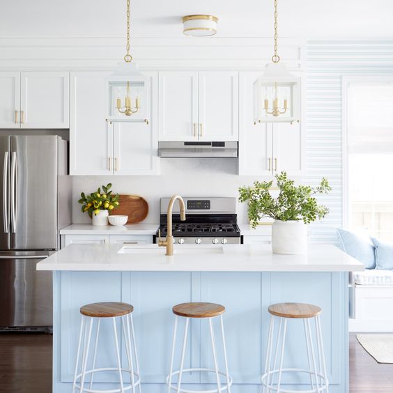 White kitchen cabinets with light blue island, gold pendant light, gold cabinet pulls, gold kitchen faucet