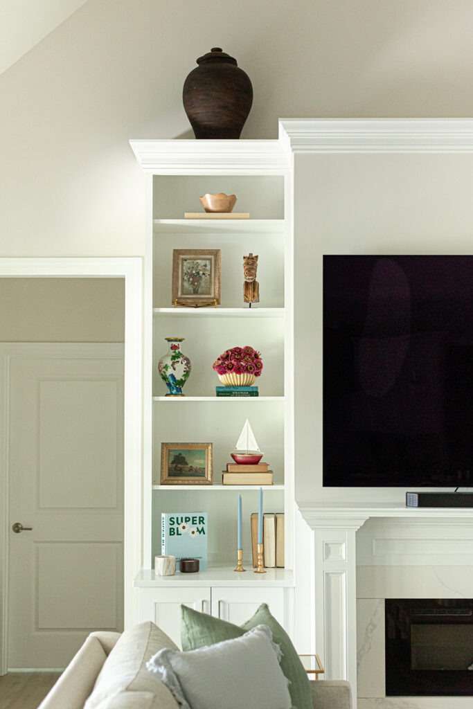 Styled built-in bookshelves with vintage-inspired art and fresh flowers in Cape Charles