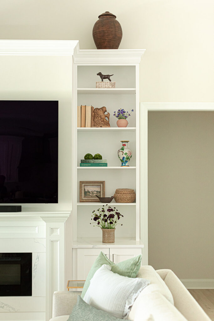 Styled built-in bookshelves with vintage-inspired art and fresh flowers in Cape Charles